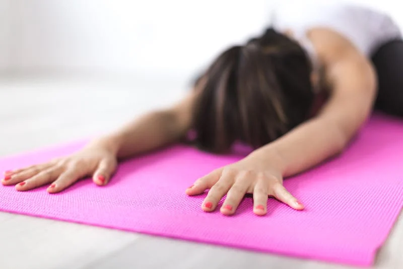 Una mujer en una tranquila posición de yoga en una playa al atardecer